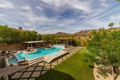 Luxurious swimming pool in a Phoenix backyard with a modern design, stone borders, and desert mountain views in the background.