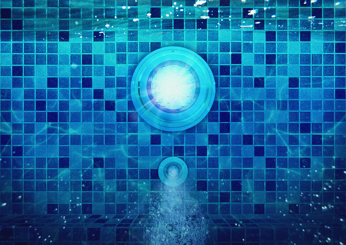 Underwater view of a glowing pool light and bubbling water jet in a tiled swimming pool
