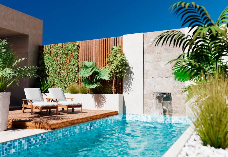 Custom-designed backyard pool with a sleek waterfall, wooden deck, and decorative plants in Phoenix