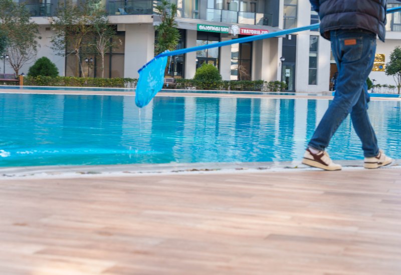 A commercial pool maintenance worker used a long-handled net to clean debris in Phoenix, AZ
